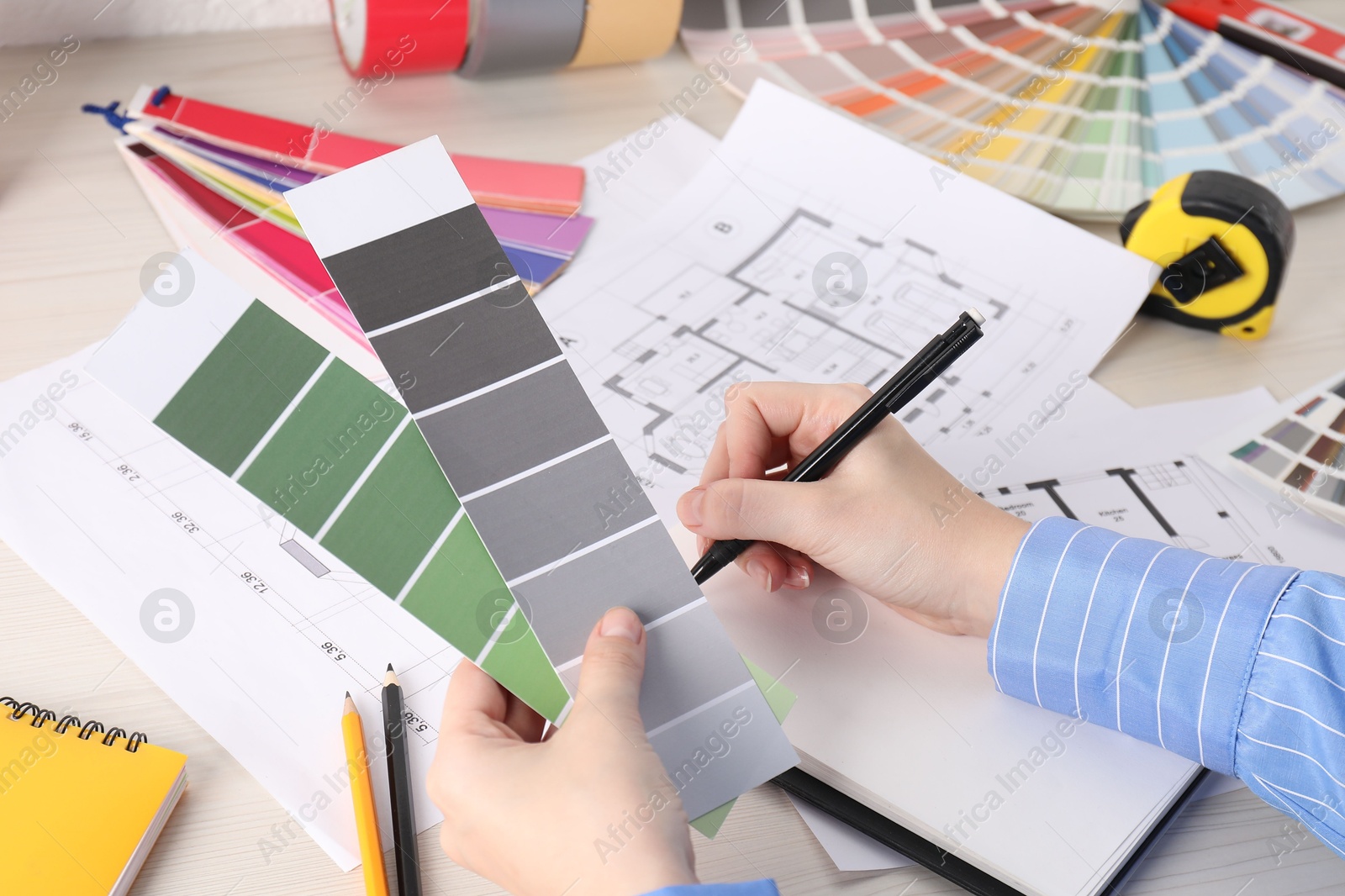 Photo of Designer with color selection chart working on house project at table, closeup