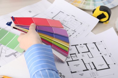 Photo of Designer with color selection chart working on house project at table, closeup