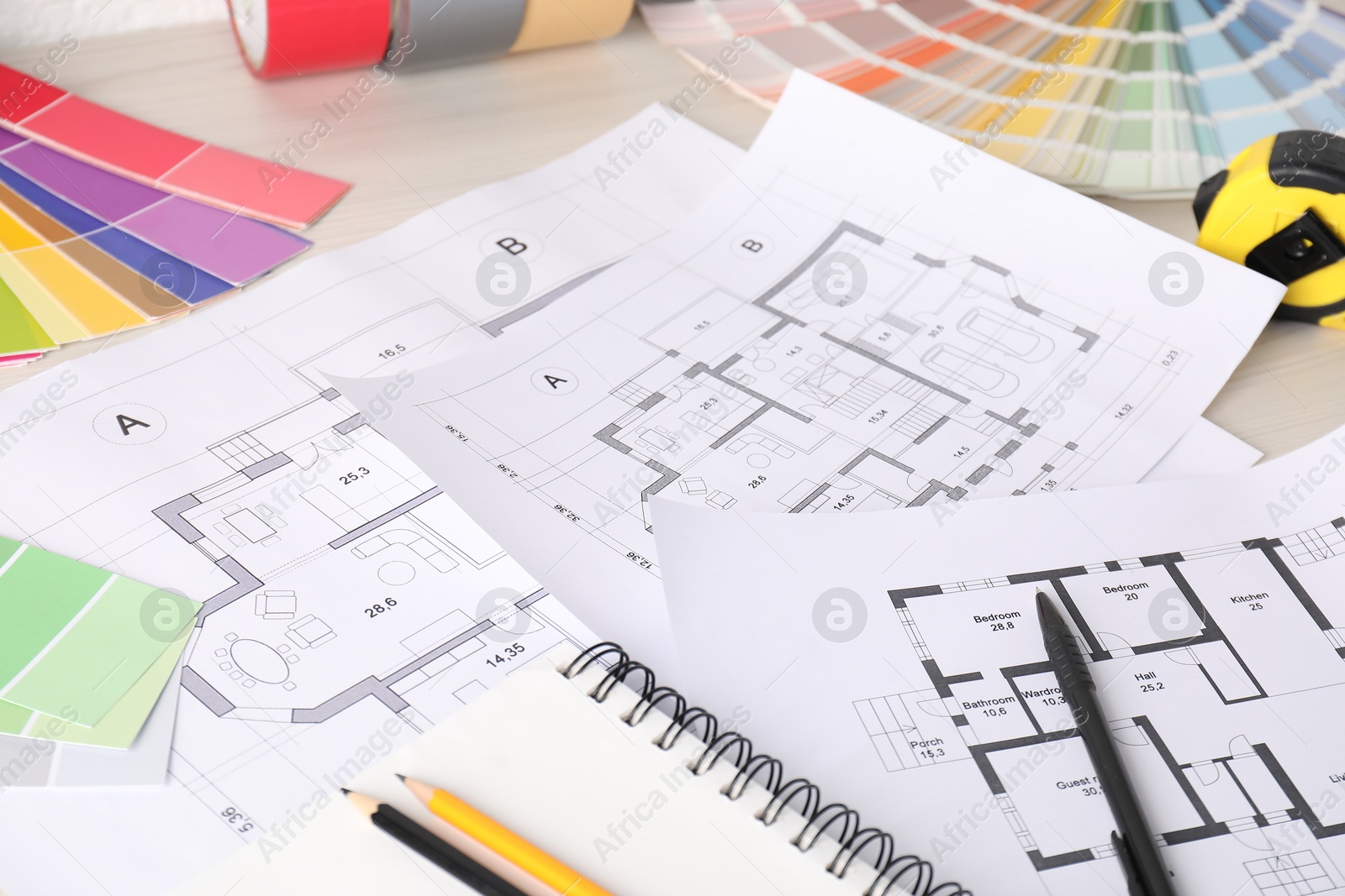 Photo of House plans, color selection charts and tape measure on white wooden table, closeup. Decorating and design