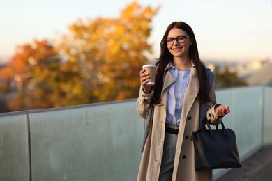 Photo of Beautiful woman in stylish suit with paper cup outdoors. Space for text