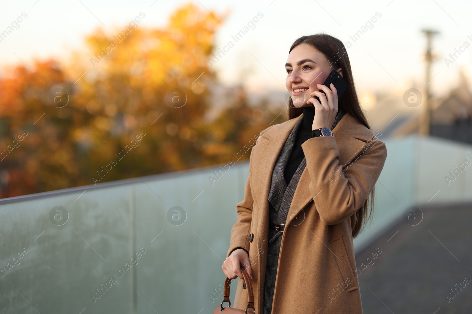 Photo of Beautiful woman in stylish suit talking on smartphone outdoors. Space for text