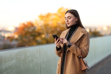 Photo of Businesswoman in stylish suit with smartphone outdoors. Space for text