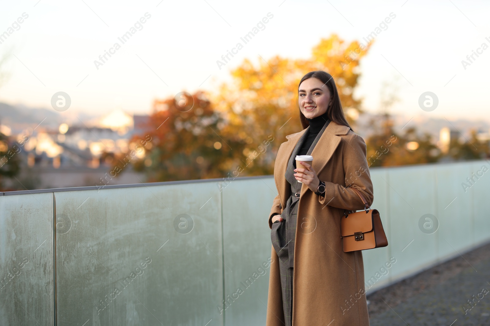 Photo of Beautiful woman in stylish suit with paper cup outdoors. Space for text