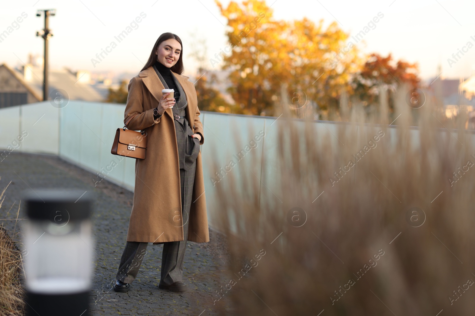 Photo of Beautiful woman in stylish suit with paper cup outdoors. Space for text