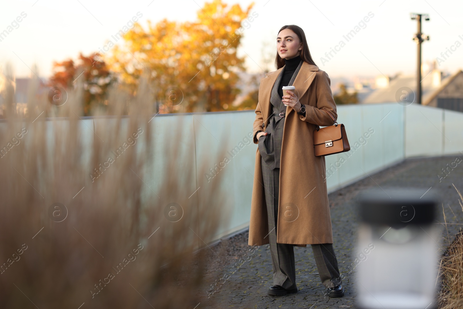 Photo of Beautiful woman in stylish suit with paper cup outdoors. Space for text