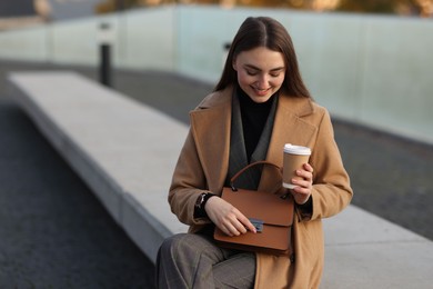 Beautiful woman in stylish suit with paper cup outdoors. Space for text