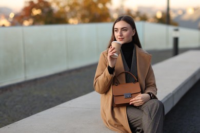 Businesswoman in stylish suit with paper cup outdoors. Space for text