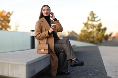 Businesswoman in stylish suit with paper cup outdoors