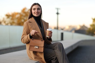 Beautiful woman in stylish suit with paper cup outdoors. Space for text