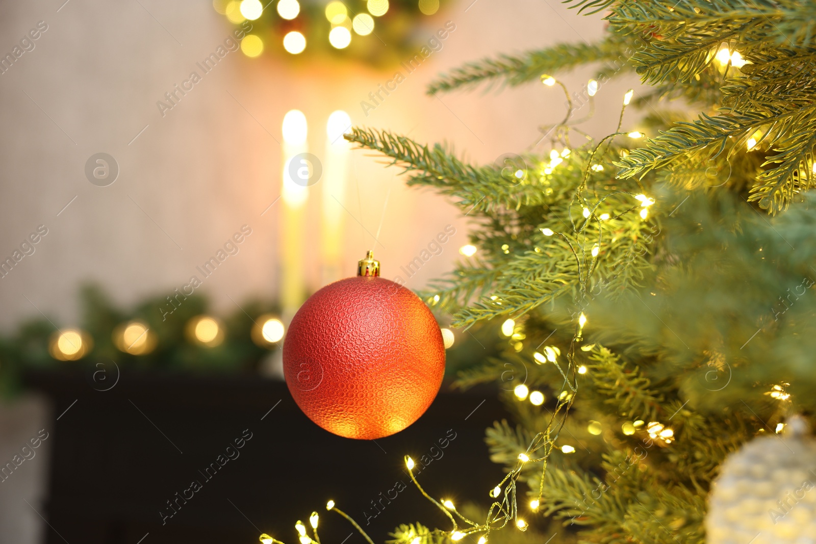 Photo of Christmas tree decorated with bauble and festive lights indoors, closeup