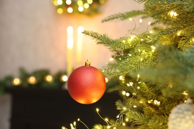 Christmas tree decorated with bauble and festive lights indoors, closeup