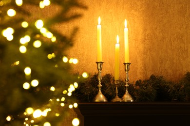 Christmas tree decorated with festive lights, burning candles and garland indoors, selective focus