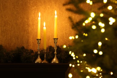 Christmas tree decorated with festive lights, burning candles and garland indoors, selective focus