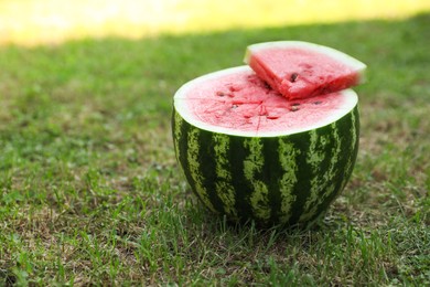 Photo of Cut juicy watermelon on green grass outdoors