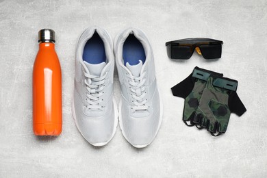 Photo of Bicycle accessories, thermo bottle and sneakers on grey textured background, flat lay