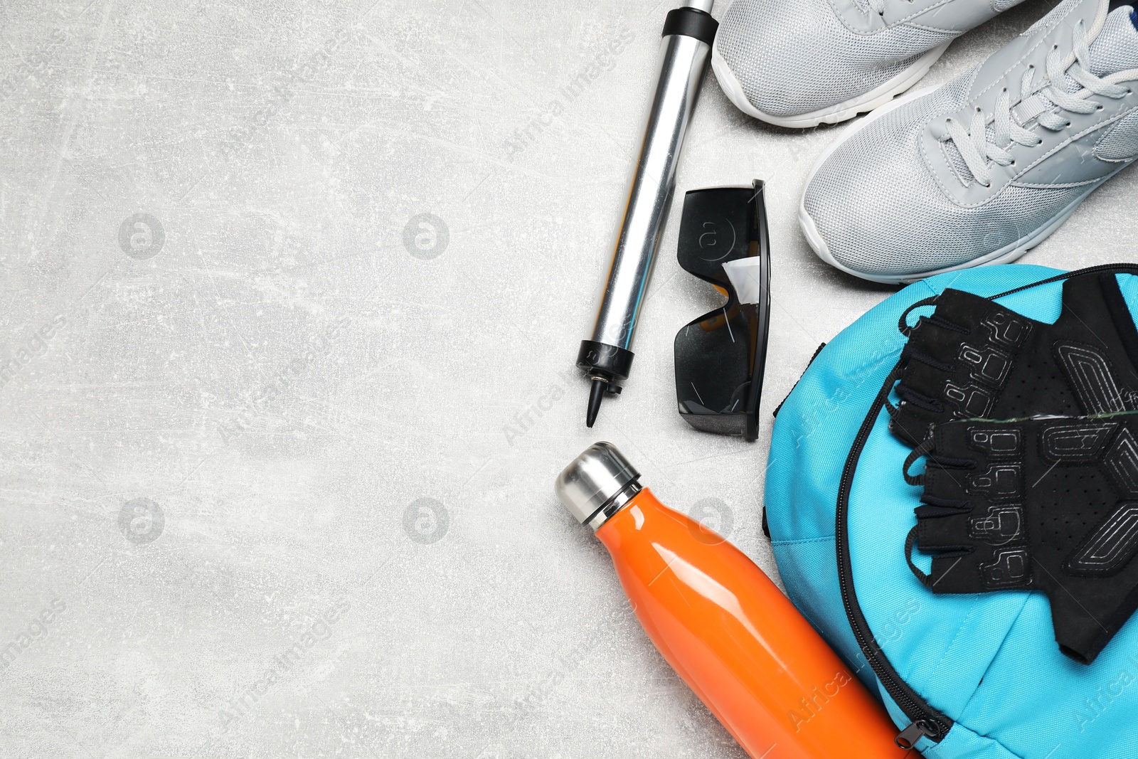 Photo of Bicycle accessories, thermo bottle, pump and sneakers on grey textured background, flat lay. Space for text