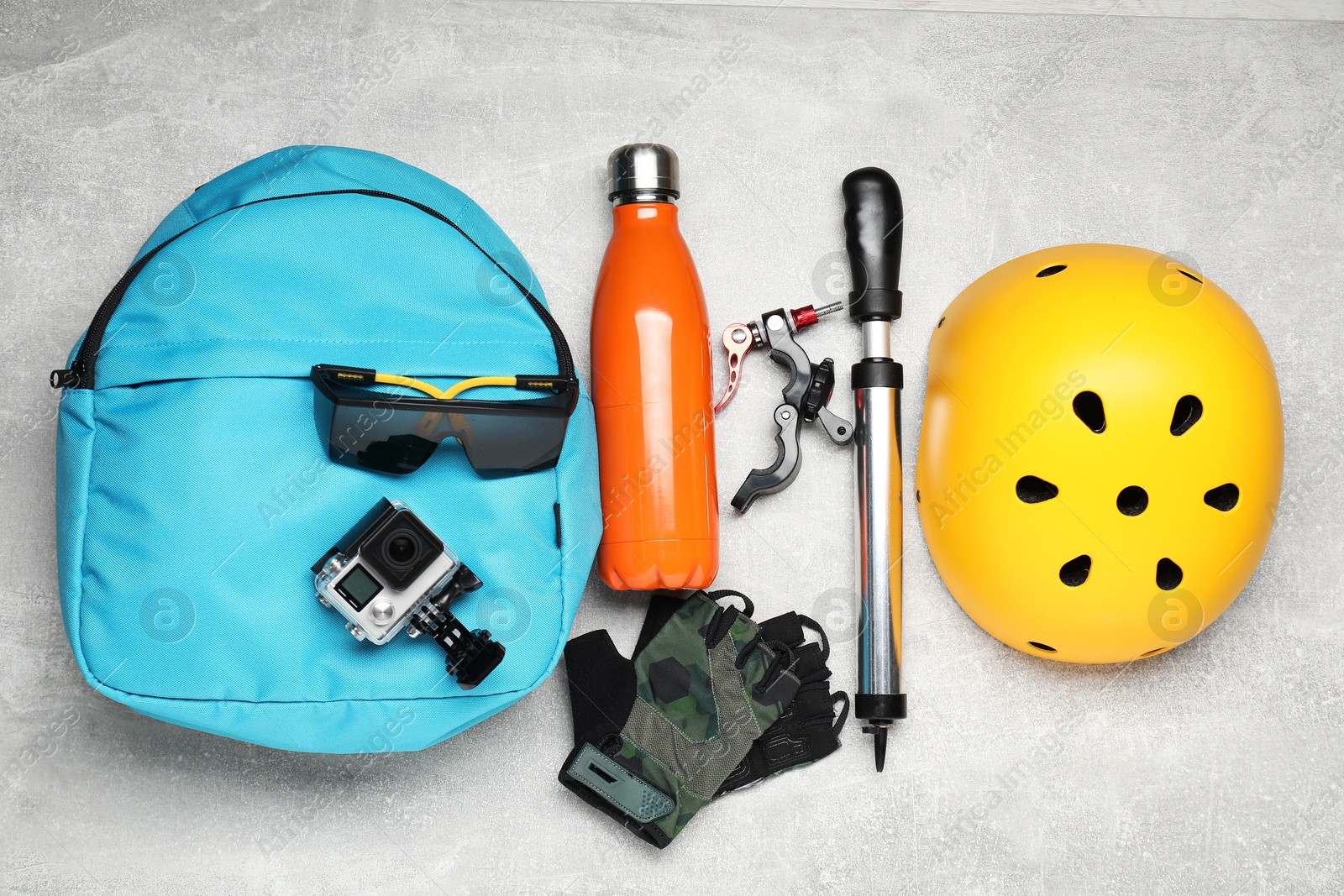 Photo of Bicycle accessories, thermo bottle and pump on grey textured background, flat lay