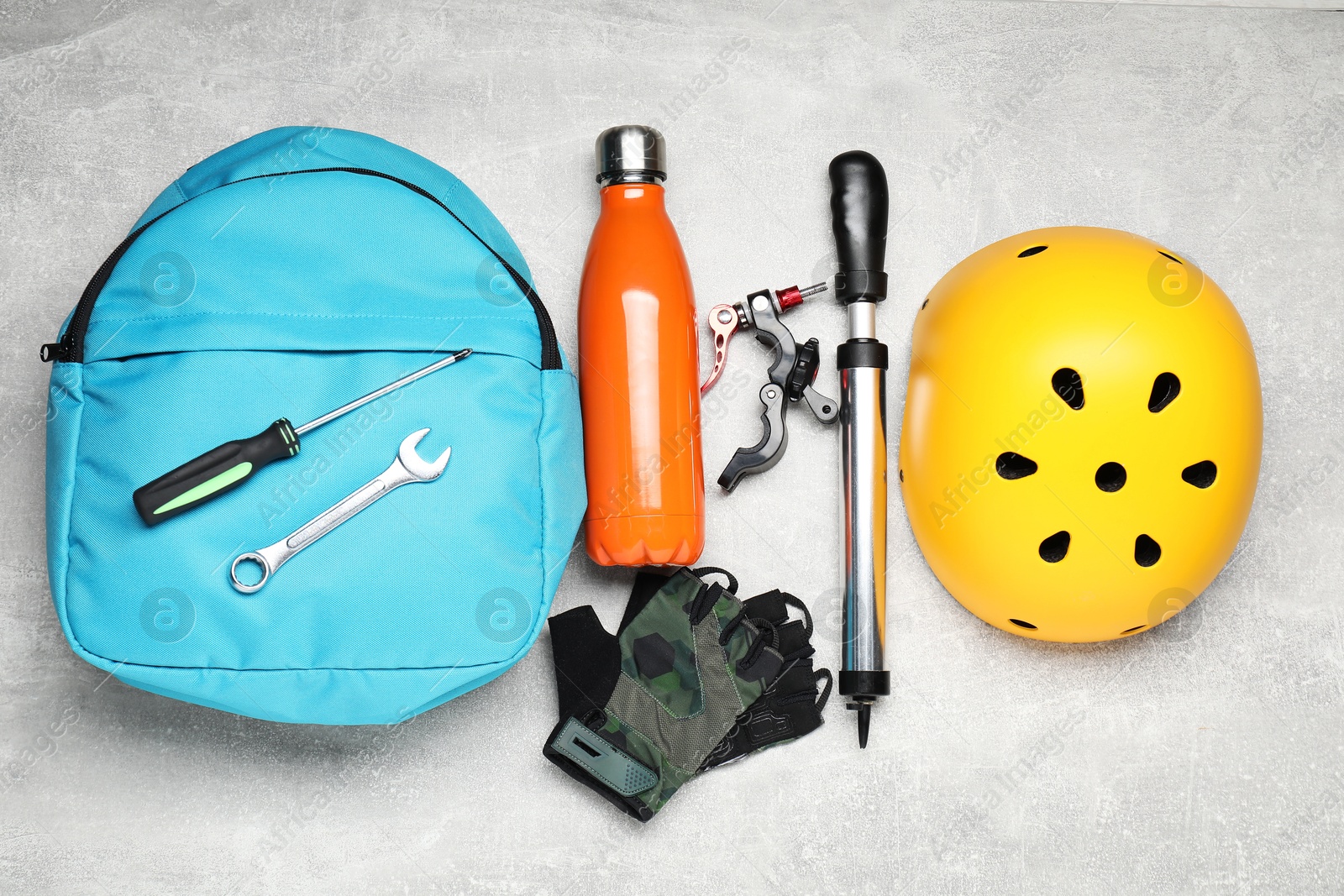 Photo of Bicycle accessories, thermo bottle and pump on grey textured background, flat lay