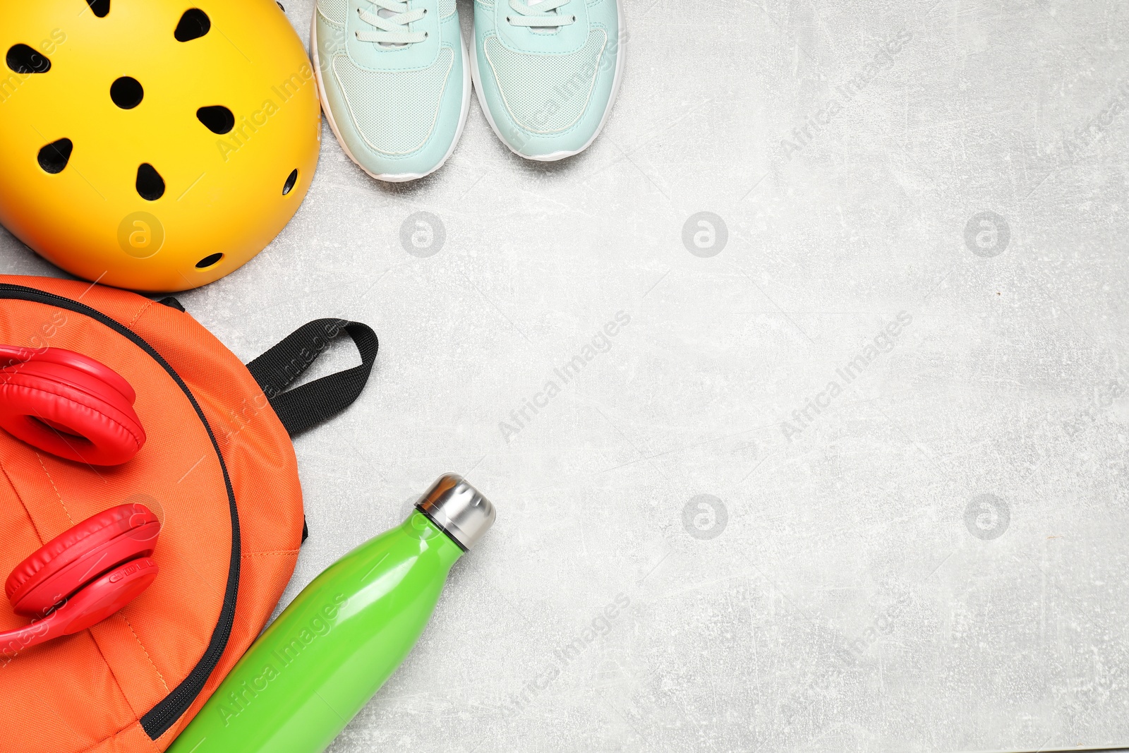 Photo of Bicycle helmet, backpack, thermo bottle and sneakers on grey textured background, flat lay. Space for text