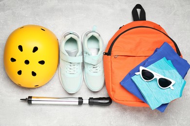 Photo of Bicycle accessories, sneakers and pump on grey textured background, flat lay