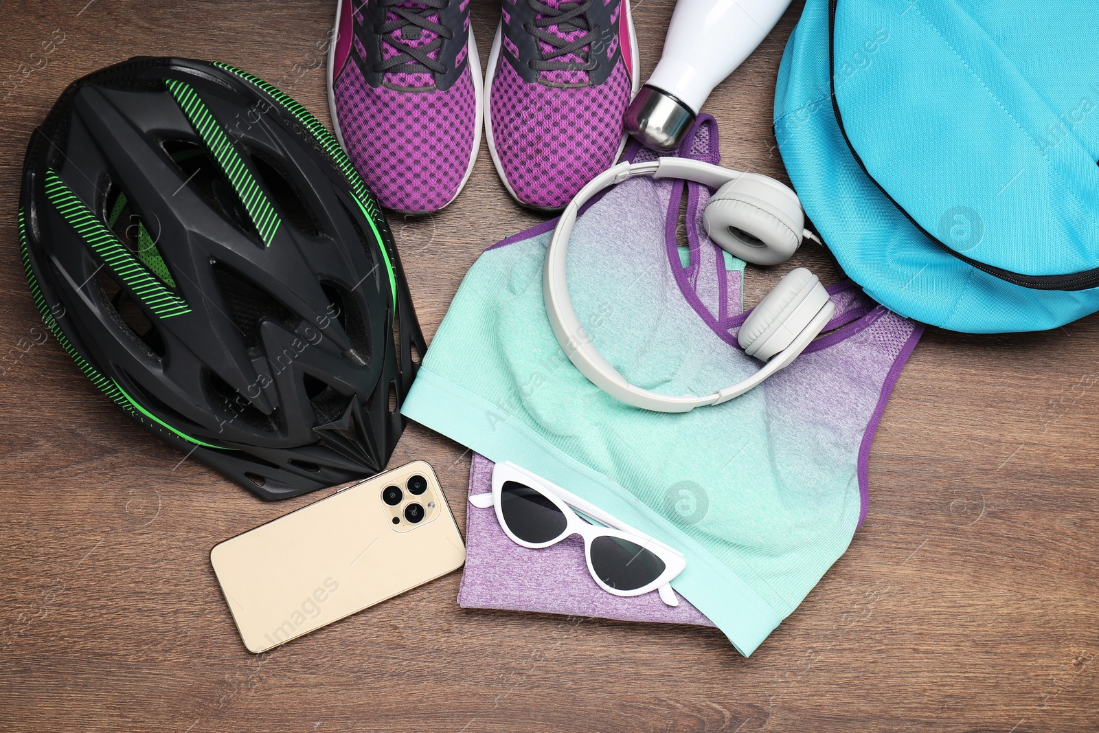 Photo of Bicycle accessories, smartphone and headphones on wooden background, flat lay