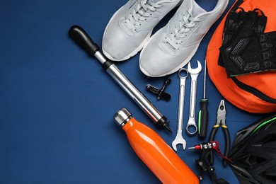 Photo of Bicycle accessories and tools on blue wooden background, flat lay. Space for text