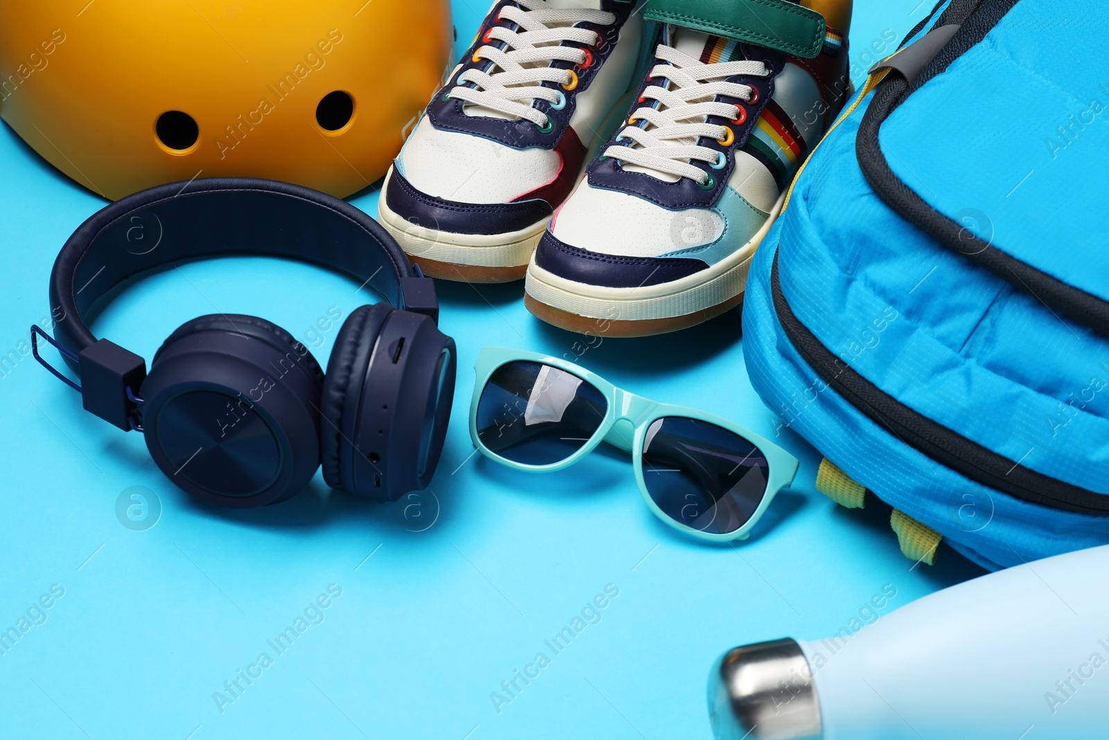 Photo of Bicycle helmet, accessories and sneakers on light blue background