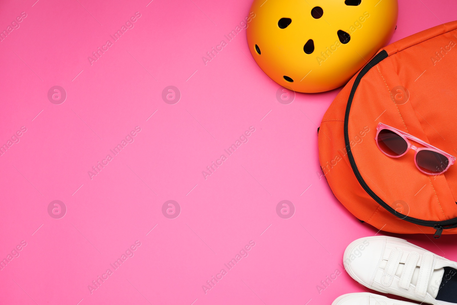 Photo of Bicycle helmet, backpack, sunglasses and sneakers on pink background, flat lay. Space for text