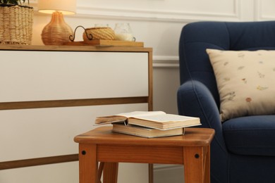 Photo of Stool, books, armchair and chest of drawers at home