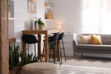 Photo of Bar stools near table in room. Interior design