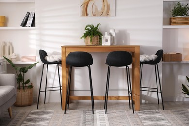 Photo of Bar stools near table in room. Interior design