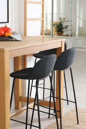 Photo of Bar stools near wooden table in room