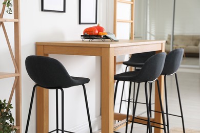 Photo of Bar stools near wooden table in room