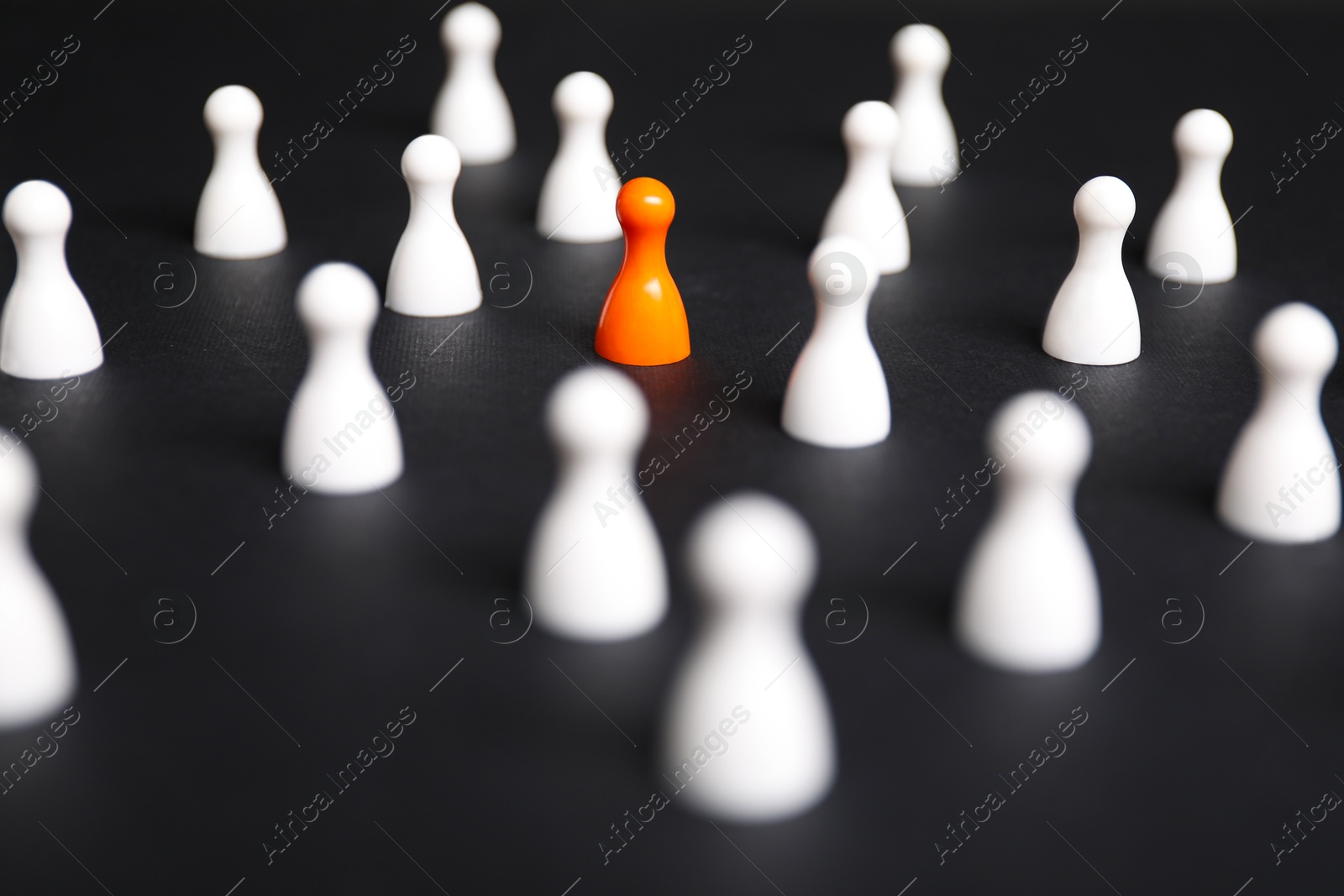 Photo of Winner concept. Orange piece among white ones on black background, selective focus