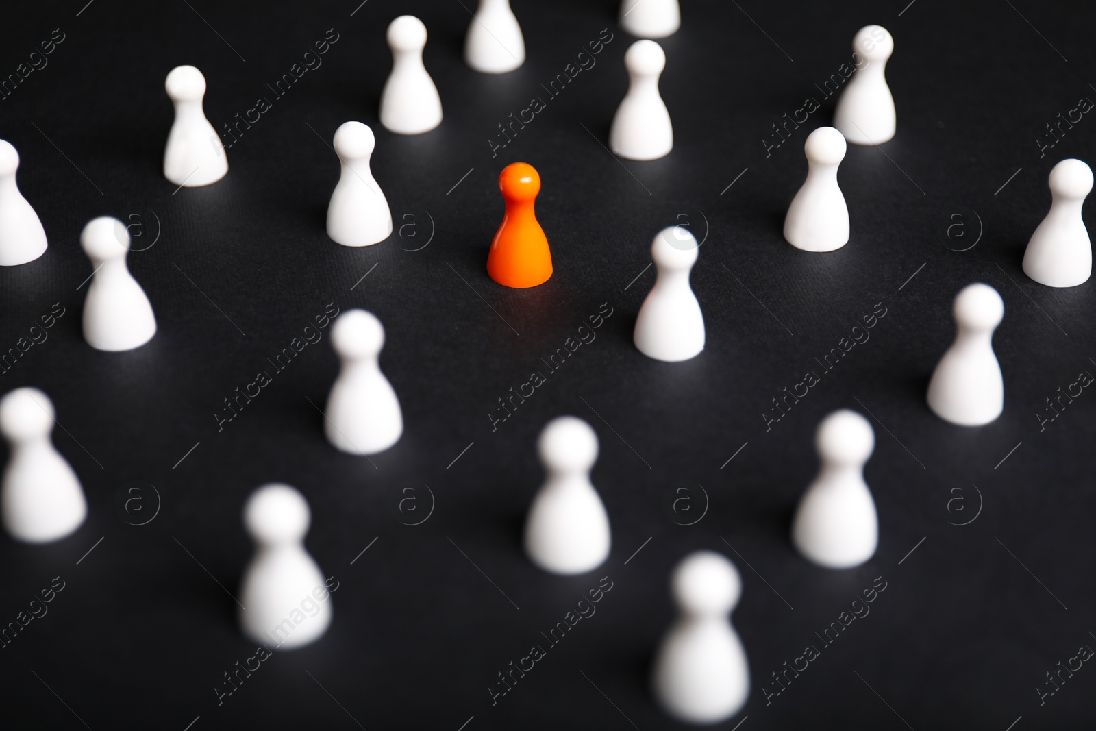 Photo of Winner concept. Orange piece among white ones on black background, selective focus