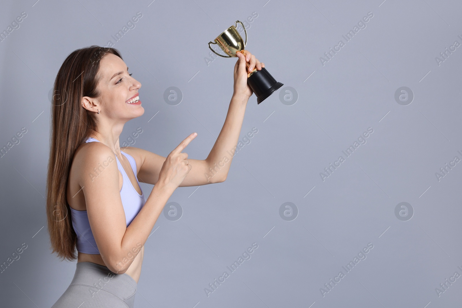 Photo of Happy winner with gold trophy cup on gray background, space for text