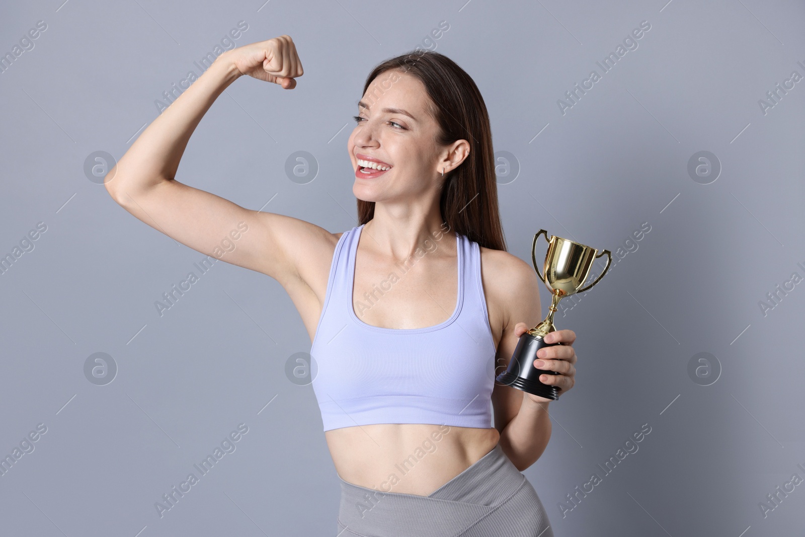 Photo of Happy winner with gold trophy cup on gray background