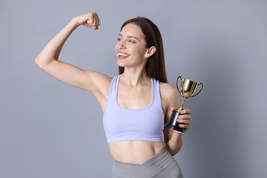 Happy winner with gold trophy cup on gray background