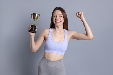 Happy winner with gold trophy cup on gray background