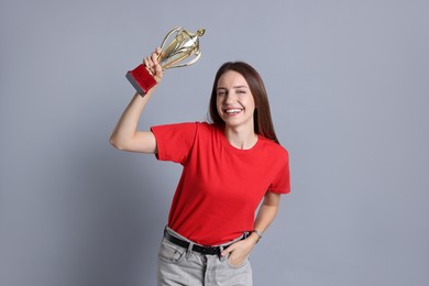 Happy winner with gold trophy cup on gray background