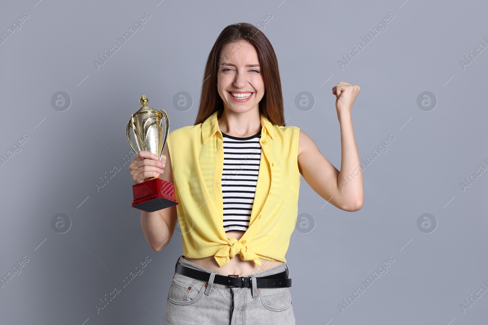 Photo of Happy winner with gold trophy cup on gray background