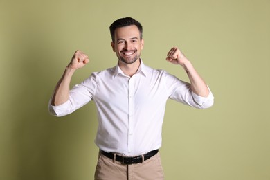 Portrait of happy winner on pale olive background