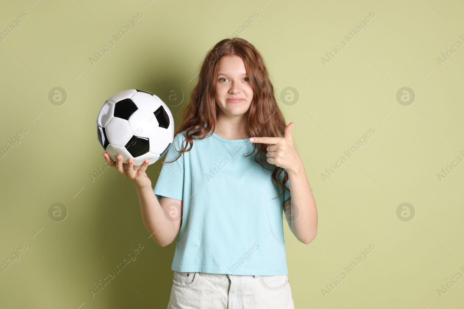 Photo of Cute teenage girl pointing at soccer ball on green background