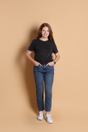 Photo of Smiling teenage girl posing on beige background