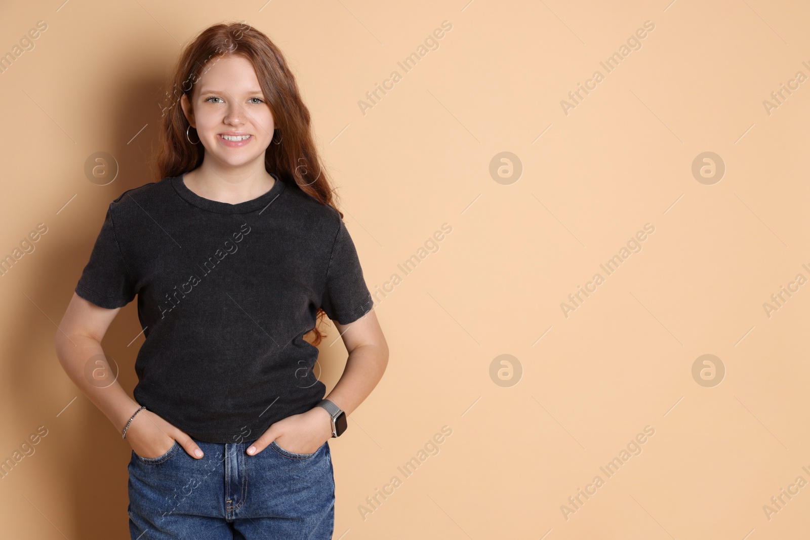 Photo of Smiling teenage girl posing on beige background. Space for text