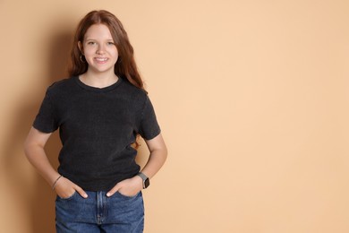 Smiling teenage girl posing on beige background. Space for text