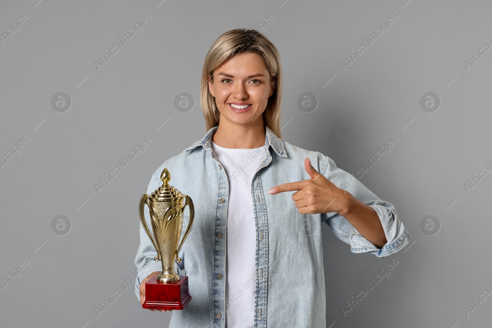 Photo of Happy winner with golden trophy cup on gray background