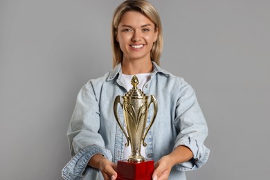 Photo of Happy winner with golden trophy cup on gray background