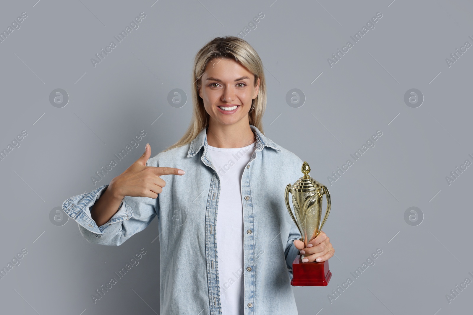 Photo of Happy winner with golden trophy cup on gray background