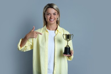 Photo of Happy winner with golden trophy cup on gray background,